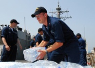 Cryptologic Technician 1st Class Jed Morris stacks bottles of water aboard USS McFaul (DDG 74). Donated items include hygiene items, baby food and infant supplies. U.S. Navy photo by Mass Communication Specialist 3rd Class Eddie Harrison.