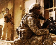 February 19, 2008. A U.S. Soldier with 1st Battalion, 504th Parachute Infantry Regiment, provides security while a member of Abna'a Al Iraq, a security group contracted by the U.S. government, calls in support before searching the last known location of a wanted man in Rusafa, Baghdad, Iraq.