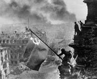 A Red Army soldier raises the Soviet Flag over the Reichstag. (Yevgeny Khaldei)