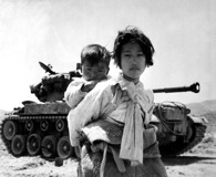 June 9, 1951. With her brother on her back a war weary Korean girl tiredly trudges by a stalled M-26 tank at Haengju, Korea. Click to enlarge. (National Archives)