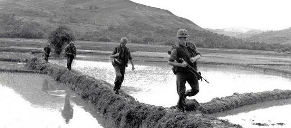 Men of H Company, 2nd Battalion, 7th Marine Regiment, move along rice paddy dikes in pursuit of Viet Cong. December 10, 1965. (National Archives)