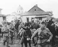 July 1942. Italian soldiers wrangle mules in a Russian village.